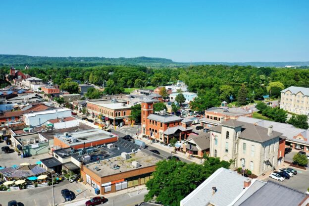 Aerial view of downtown Milton featuring historic brick buildings, tree-lined streets, and the picturesque Niagara Escarpment.