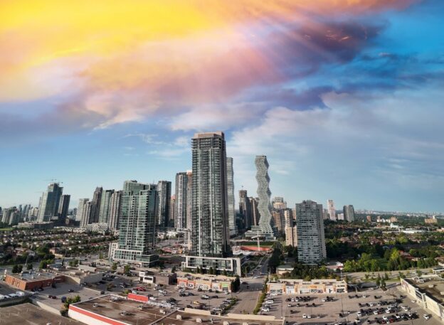 Aerial view of downtown Mississauga featuring modern skyscrapers, including the iconic Marilyn Monroe Towers, under a vibrant sky.