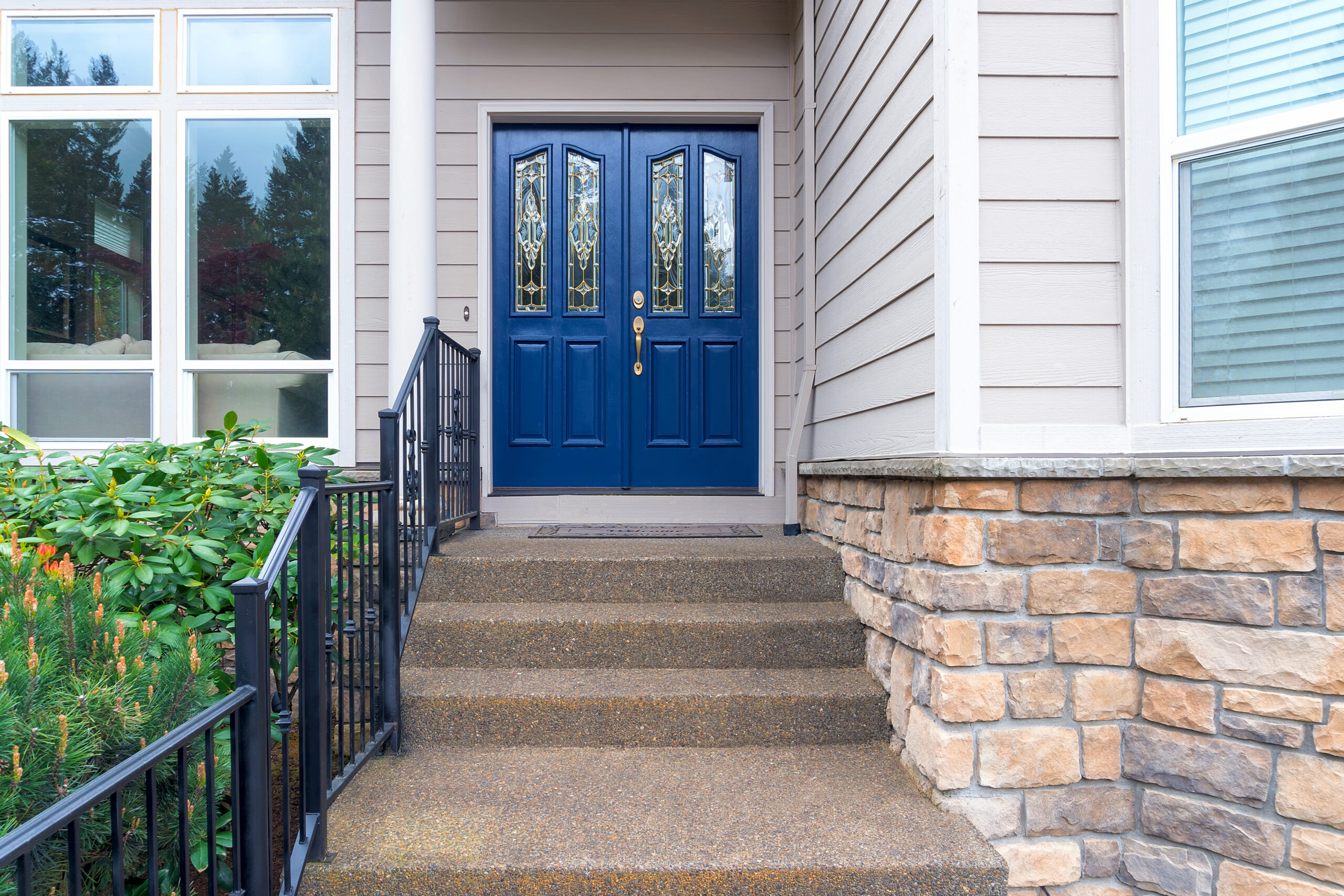  Alt text - Elegant navy-blue double panel doors with decorative glass inserts at the entrance of a modern home with stone and siding exterior.