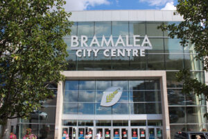 Exterior view of Bramalea City Centre in Brampton, Ontario, featuring large glass windows, modern architecture, and the main entrance with shoppers walking in and out.