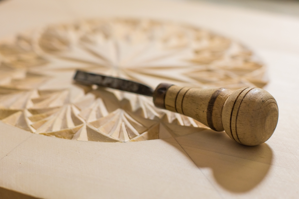 Handcrafted wood carving detail showing artisan chisel work on custom millwork design.