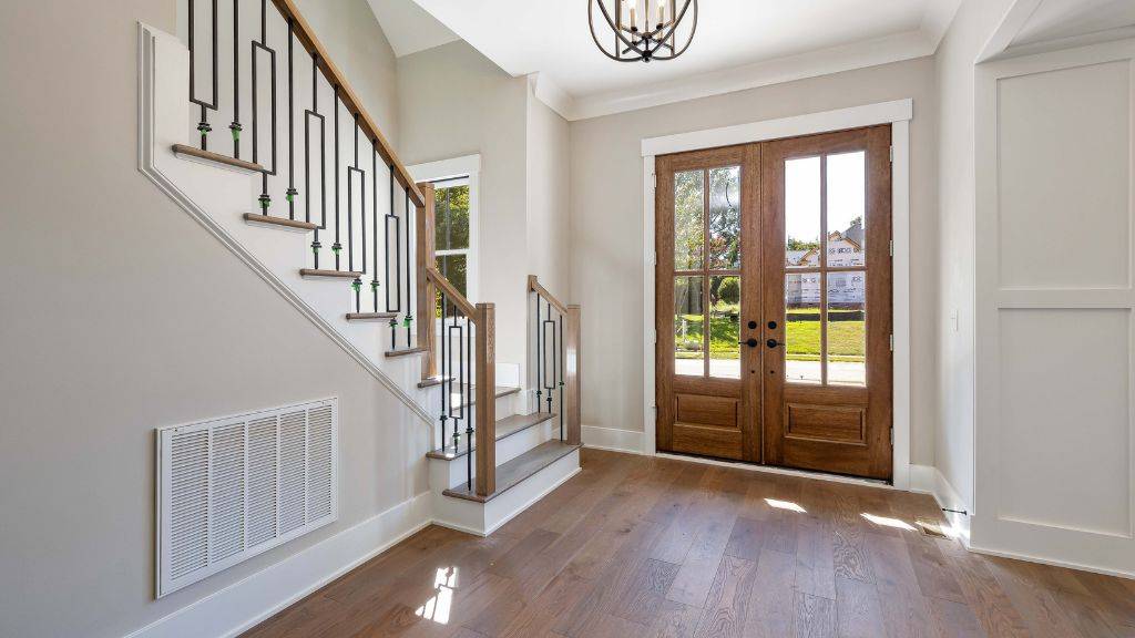 Foyer with matching white baseboards, door casing, and crown molding complementing custom double glass wood doors. 