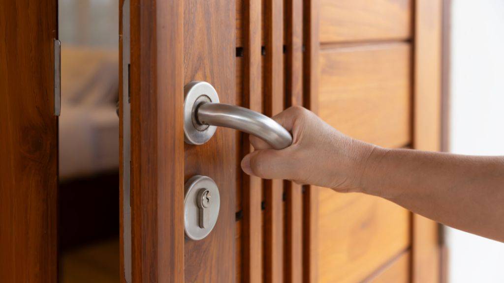 Hand opening a custom solid wood interior door with modern stainless steel hardware.