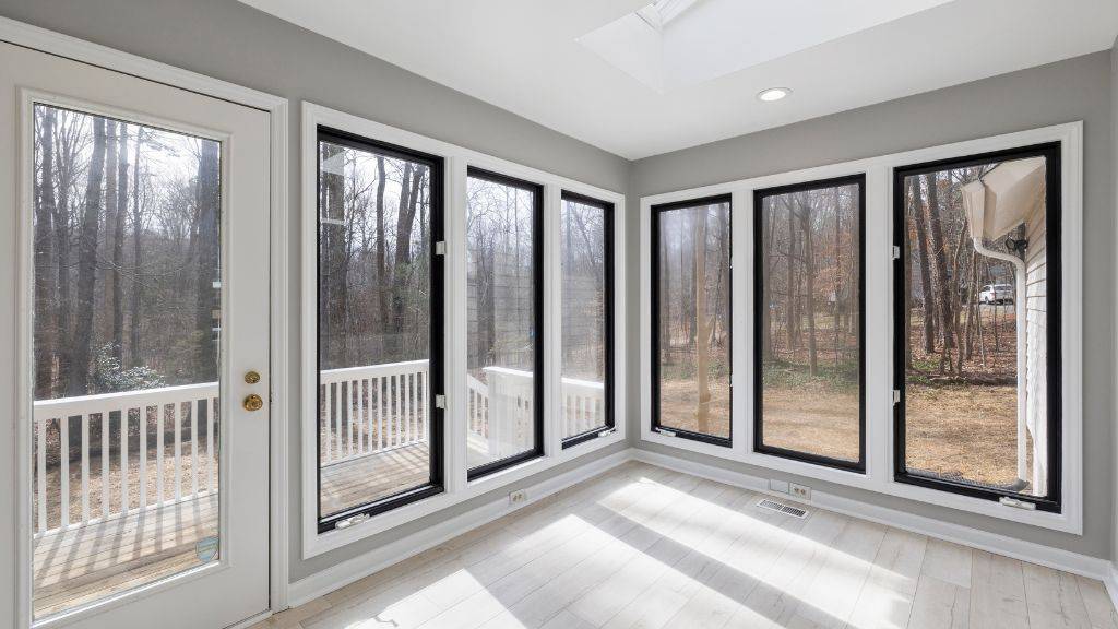 Sunroom featuring modern black vinyl replacement windows and a white patio door installed 
